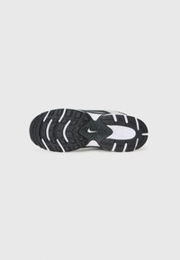 Nike athletic shoe sole features a black rubber outsole with white accents, textured grip areas, and a central branding detail.