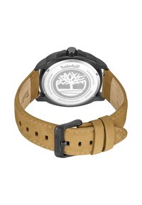 Orologio Timberland con cassa in acciaio inossidabile nero, cinturino in suede color nocciola e fibbia in metallo. Sul retro è visibile il logo Timberland.
