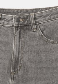 Nahaufnahme des Bunds grauer Jeans mit Metallknopf, Gürtelschlaufe, Tasche und sichtbaren Nähdetails.
