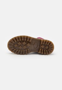 Semelle de botte en caoutchouc avec un profond relief pour une bonne traction, surface texturée marron et accents roses sur les côtés.