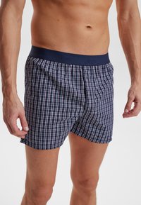 Námořnické kostkované boxerky s měkkým, elastickým pasem. Vzor obsahuje tenké bílé a červené čáry. Vyrobeno z lehkého materiálu.