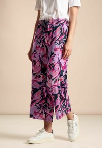 Bloemrijke, wijde broek met een donkere achtergrond met grote roze en paarse bloemen. Elastische tailleband met een koord voor de pasvorm.