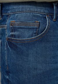 Donkerblauwe denim jeans met een klassieke rechte snit, met contrasterende stiksels, een achterzak en een zachte textuur.