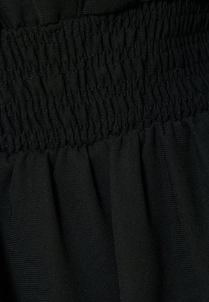Tejido negro con textura de fruncido en la cintura, con drapeados suaves y fluidos debajo. El material parece ligero y suave.