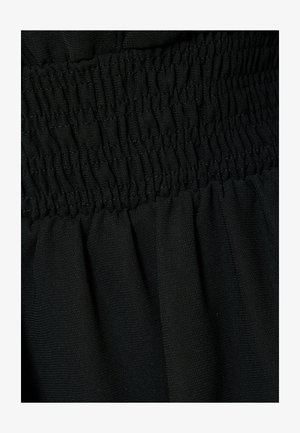 Mustaa kangasta, jossa on keräilty smokkitekstuuri vyötäröllä, ja pehmeät, virtaavat laskokset alapuolella. Materiaali näyttää kevyeltä ja sileältä.