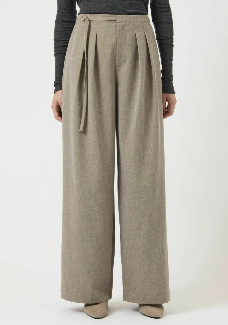 Pantaloni a gamba larga in tessuto grigio chiaro con una texture sottile. Presentano pieghe frontali, chiusura laterale con bottoni e dettaglio in vita con laccio.
