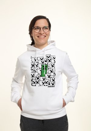 Felpa bianca con cappuccio che presenta una grafica di molteplici facce di creeper di Minecraft in nero con un creeper verde. Tessuto morbido, vestibilità regolare, cappuccio con coulisse.