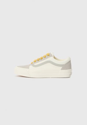 Grå og kremfarget kanvas sneaker med gule snørebånd, lavt design og teksturert sidemodul, med en hvit gummisåle.