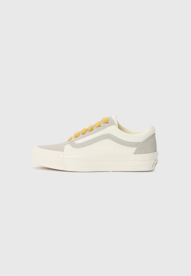 Gray and cream canvas sneaker with yellow laces, a low-top design, and a textured side panel, featuring a white rubber sole.