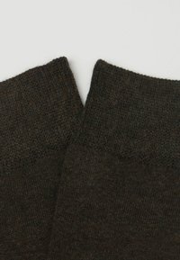 Brune strikkede sokker med en struktureret overflade og ribbet kant, lavet af et blødt og fleksibelt materiale for komfort.
