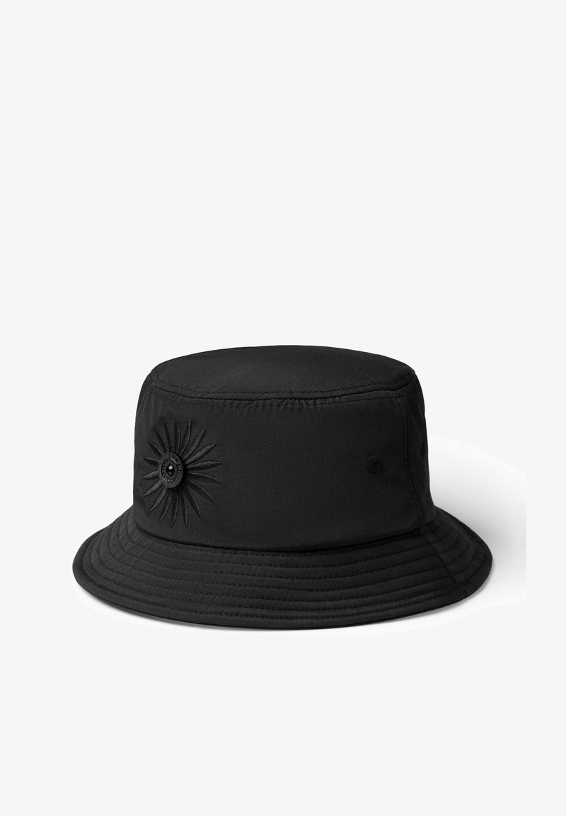 Svart bucket hat av tyg med sydd solfjäderdesign och en knappdetalj på sidan; har en bred, platt skärm.