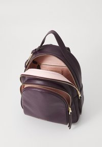 Sac à dos en cuir violet avec quincaillerie dorée, comportant plusieurs compartiments zippés et une doublure intérieure rose doux.