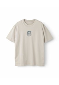 T-shirt beige à manches courtes avec un petit graphique bleu d'une boîte de sardines ouverte contenant trois poissons, centré sur la poitrine.