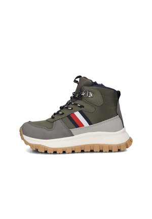 Hikingboots geïnspireerd door herenmode, gemaakt van olijfgroen synthetisch materiaal met grijze accenten, een witte zool en een rood/blauw gestreept detail aan de zijkant.