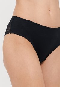 Zwarte katoenen slips met een zachte textuur, voorzien van een kant afgewerkte tailleband en zijaccenten. Klassiek low-rise ontwerp.