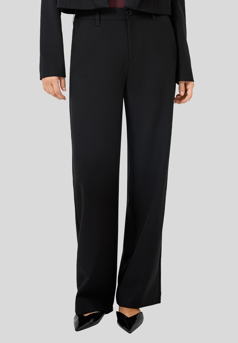 Pantalons large noirs en tissu lisse, avec une taille mi-haute, des passants de ceinture et un détail de couture discret le long des jambes.