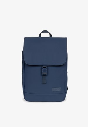 Mochila rectangular azul con una solapa asegurada por un broche de plástico en la parte delantera y un asa de transporte en la parte superior, mostrada sobre un fondo blanco.