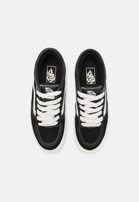 Black suede sneakers with white laces, featuring a classic design and contrasting white stripe on the sides. Textured upper and rubber sole.