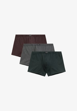 Trzy pary męskich bokserków w kolorze bordowym w czarne kropki, jednolitym szarym oraz ciemnozielonym w białe kropki, ułożonych w nakładkę na białym tle.