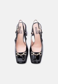 Μαύρες γόβες slingback από δερμάτινο λουστρίνι με τετράγωνα δάχτυλα, χρυσές λεπτομέρειες σε σχήμα αλογόμυτης και το λογότυπο "LOVE MOSCHINO" στις μπεζ εσωτερικές σόλες.