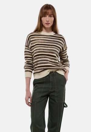 Pull rayé en crème, marron et marron foncé, avec un col et des poignets côtelés. Associé à un pantalon cargo vert foncé avec des poches.