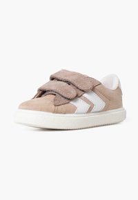 Beige suede sneaker with white leather accents, dual Velcro straps, rounded toe, and rubber sole featuring a textured tread pattern.