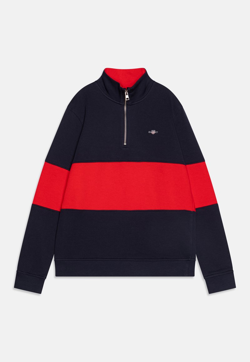 Jūras un sarkanā krāsā blokota sporta krekls ar augstu apkakli, puskabatas aizdari un izšūtu logotipu uz krūšu daļas. Mīksts materiāls, garas piedurknes.