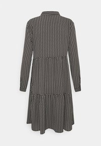 Klänning med svart-vitt mönster, krage, långa ärmar, lager-på-lager nederdel och avslappnad passform, tillverkad av lättviktsmaterial.