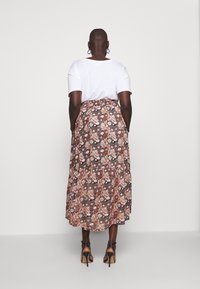 Spódnica maxi: wzór w kwiaty w odcieniach różu, pomarańczu i czerni; połączona z gładką białą koszulką; dopasowana, do kostek z rozkloszowanym dołem.