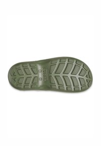Semelle verte d'une chaussure avec un motif texturé, présentant des surfaces de prise surélevées et un logo central. Design avec un bout courbé et un talon arrondi.