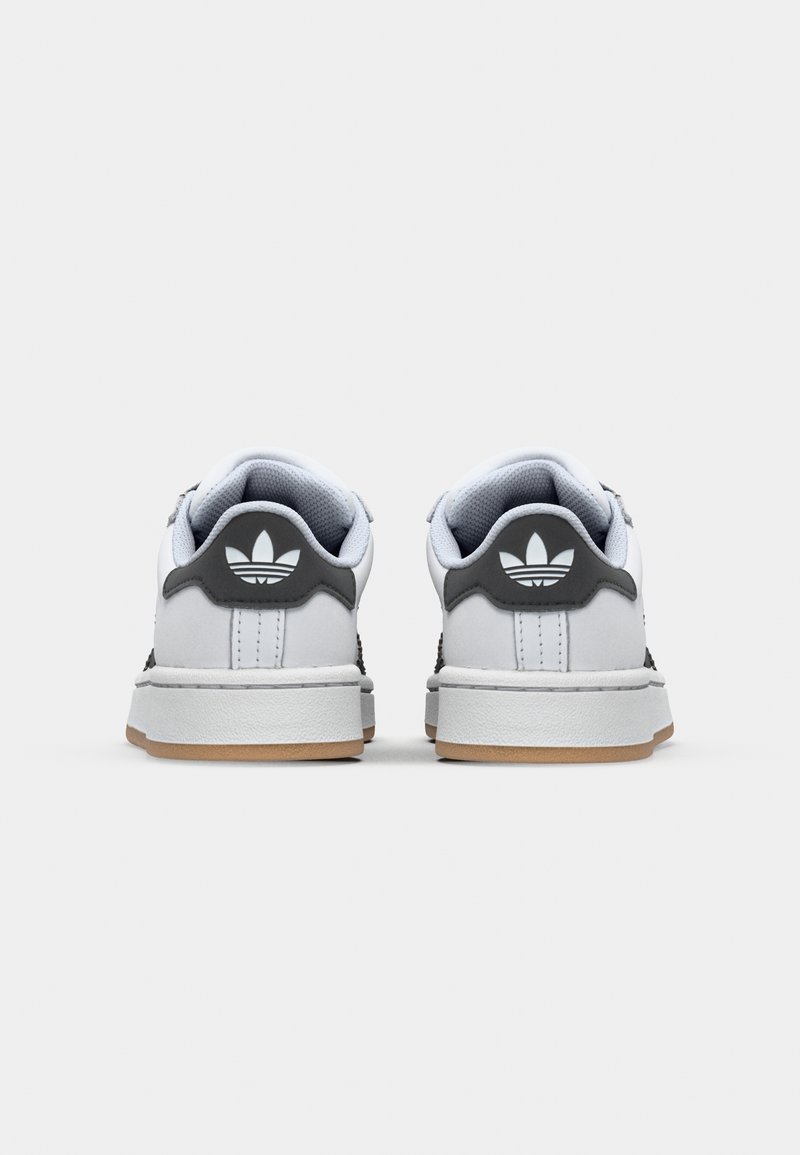 Zapatillas blancas y grises con parte superior de cuero texturizado, cuello acolchado y suela de goma. Cuenta con un logo negro en la parte trasera.