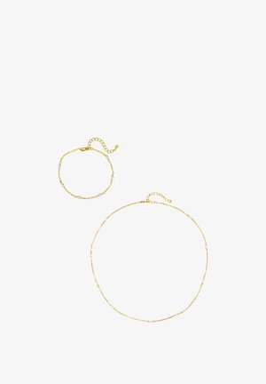 Gouden ketting halsketting en bijpassende armband, elk met kleine witte parel accenten en verstelbare sluitingen, op witte achtergrond.