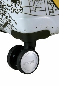 Valigia rigida bianca con design grafico nero; presenta ruote nere lisce e un accentuato argento con incisione "American Tourister".