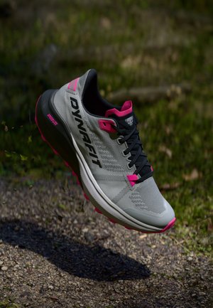 Vieglie skriešanas apavi pelēkā un rozā krāsā, ar teksturētu sieta virsu, atsitienu nodrošinošu zoli, izteiktu logotipu un izturīgu auklu sistēmu.