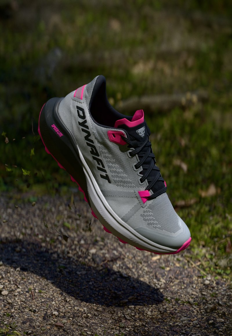 Ελαφρύ παπούτσι τρεξίματος σε γκρι και ροζ, με υφή από δίχτυ στην επάνω πλευρά, ανταγωνιστική σόλα, έντονο λογότυπο και ανθεκτικό σύστημα κορδονιών.