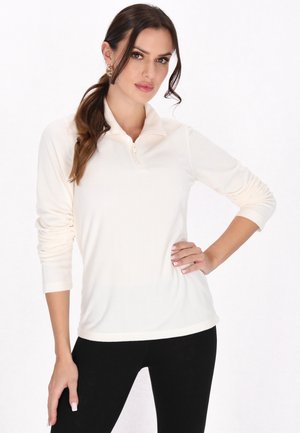 Helle Creme Pullover mit Reißverschlusskragen, langen Ärmeln und weicher Textur, kombiniert mit schwarzen Leggings.