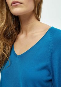Blauer V-Ausschnitt-Pullover aus weichem, strukturiertem Strick. Verfügt über feine Nähte entlang der Nähte und eine lockere Passform am Ausschnitt.