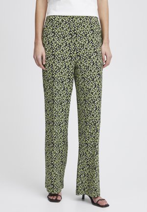 Pantalons à motif floral noirs avec des fleurs vertes et blanches, présentant une coupe décontractée et une texture de tissu lisse.