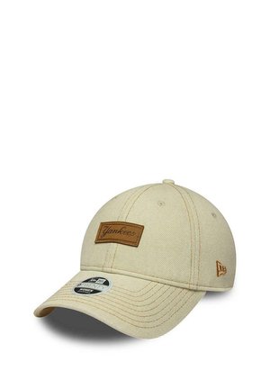 Casquette de baseball beige avec écusson marron des Yankees sur le devant et logo New Era sur le côté, présentant une visière incurvée et des détails de couture visibles.
