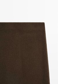 Un morceau de tissu rectangulaire marron foncé avec un bord plié sur un fond blanc.