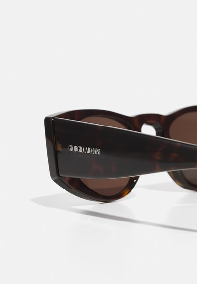 Ochelari de soare Giorgio Armani cu ramă din scoică țestoasă, lentile de culoare maro și detalii cu logo pe lateral, având un design geometric modern.