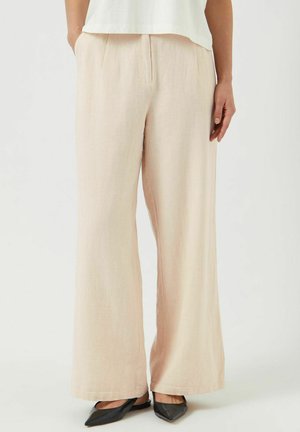 Lichtroze wijde broek van linnen, met een gestructureerde afwerking, voorplooien en een losse pasvorm, gecombineerd met zwarte puntige schoenen.