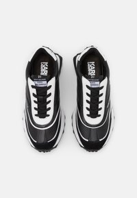 Baskets noires et blanches avec une finition en cuir lisse, des rayures contrastées et des lacets texturés. Elles disposent d'une semelle en caoutchouc épaisse pour le confort.