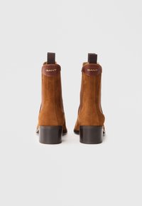 Bottines en daim marron avec un talon large solide, dotées d'accents en cuir marron et de panneaux élastiques latéraux pour un enfilage facile. Logo GANT sur le talon.