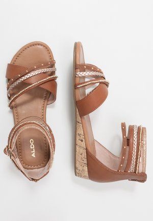 Hnědé klínové sandály s několika ozdobnými pásky, včetně pletených a korálkových vzorů, a podpatky s korkovou texturou, zobrazené z horního a bočního pohledu.