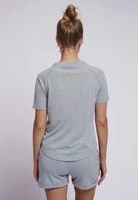 Camiseta deportiva de manga corta en gris claro con mangas raglán, escote sin costuras y un ajuste relajado, combinada con pantalones cortos a juego.