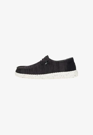 Schwarzer strukturierter Slip-On Schuh mit einer weiß gesprenkelten Sohle und einem minimalistischen Design. Verfügt über subtile Nähte und zwei kleine dekorative Akzente.