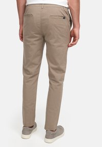 Khaki chinos med rett ben-snitt og to baklommer. Laget av bomullsstoff, med en glatt tekstur og minimale detaljer.