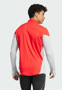 Rød og hvid langærmet atletisk skjorte med krave, slank pasform og glat tekstur. Har kontrasterende ærmer og bagdesign.