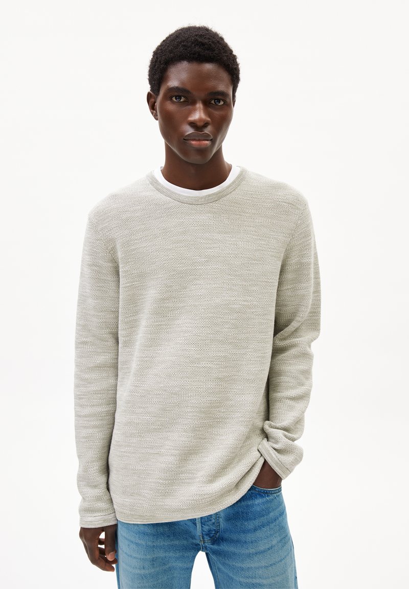 Hellgrauer strukturierter Pullover mit rundem Halsausschnitt und langen Ärmeln, kombiniert mit hellblauen Jeans; lässiger Schnitt.